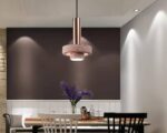 Suspension rose design contemporain, allumée et suspendue au-dessus d'une table.