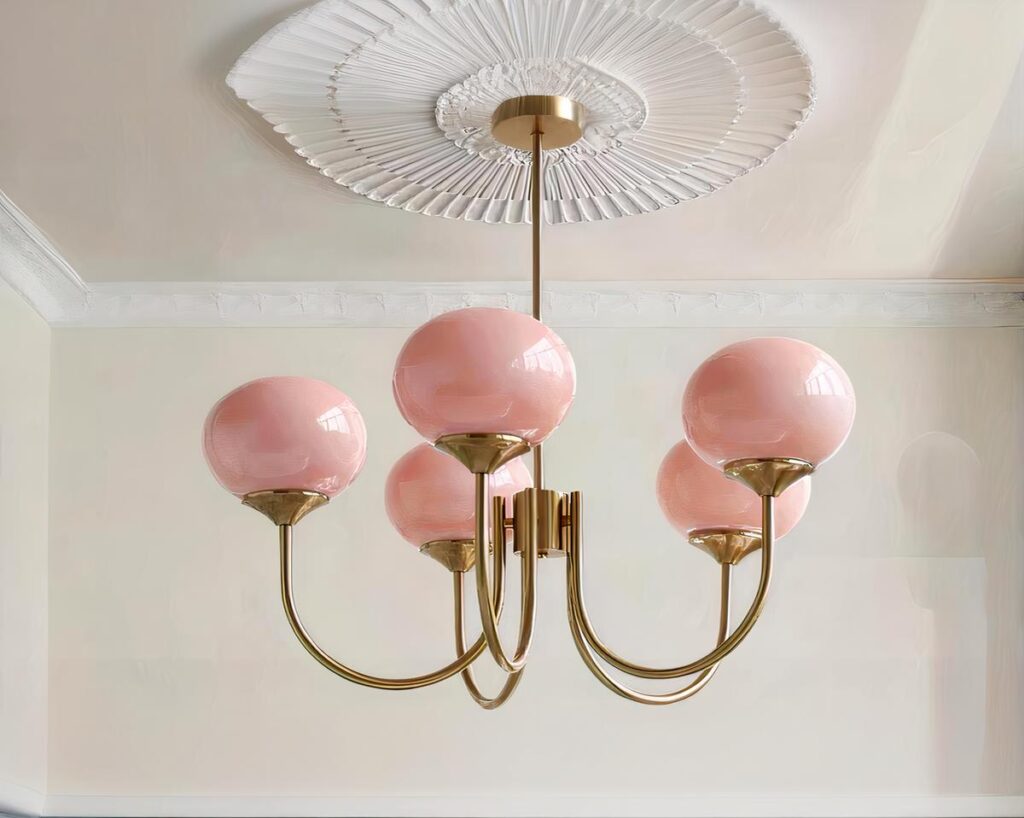 Suspension rose élégante avec globes en verre, suspendue, de couleur rose et les tiges sont de couleur dorée. Fond clair.