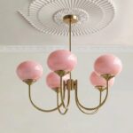 Suspension rose élégante avec globes en verre, suspendue, de couleur rose et les tiges sont de couleur dorée. Fond clair.