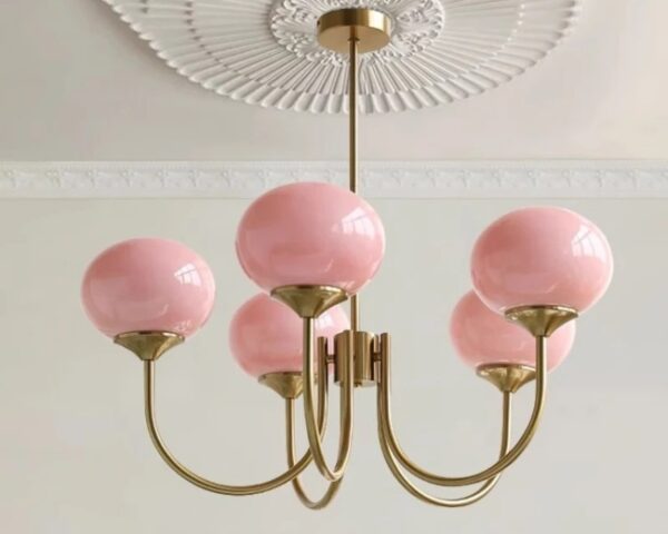 Suspension rose élégante avec globes en verre, suspendue, de couleur rose et les tiges sont de couleur dorée. Fond clair.