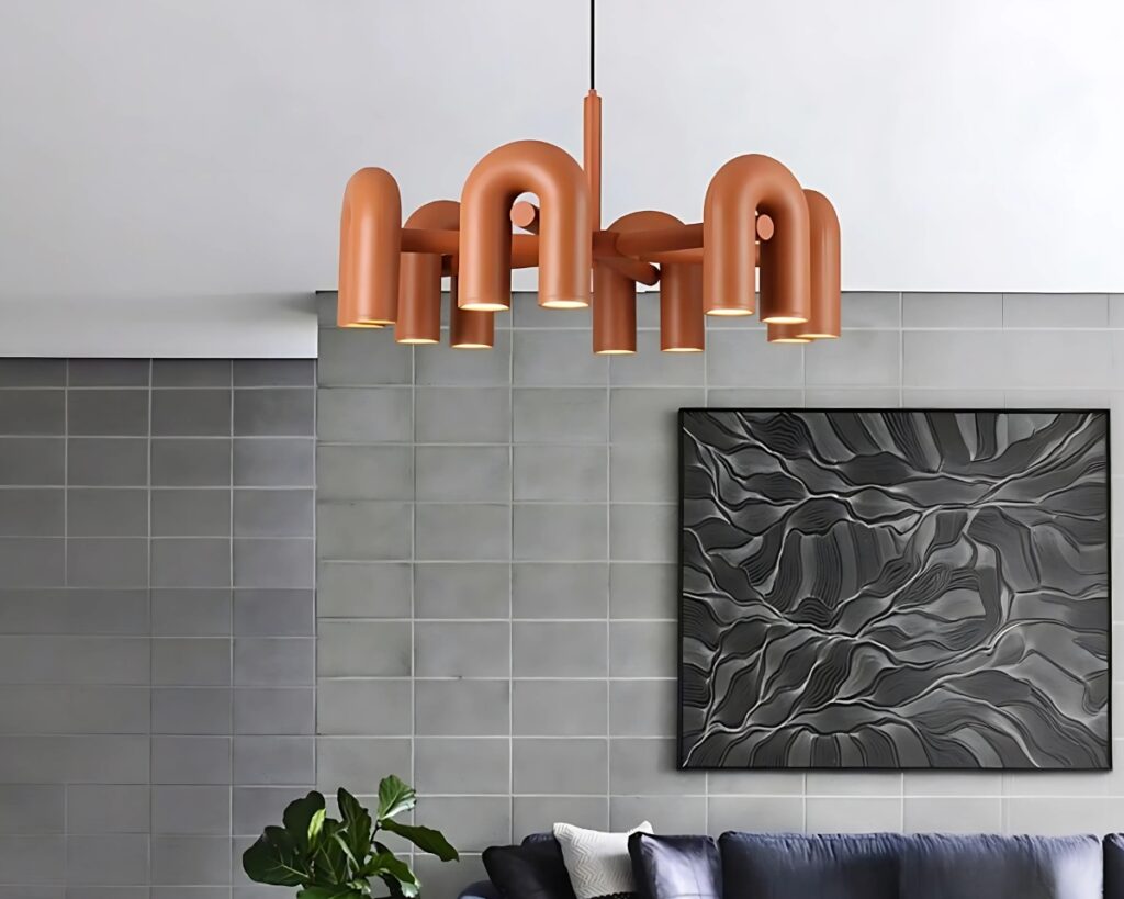 Suspension terracotta multiple en forme de U dans une pièce aux murs gris avec un tableau gris foncé.