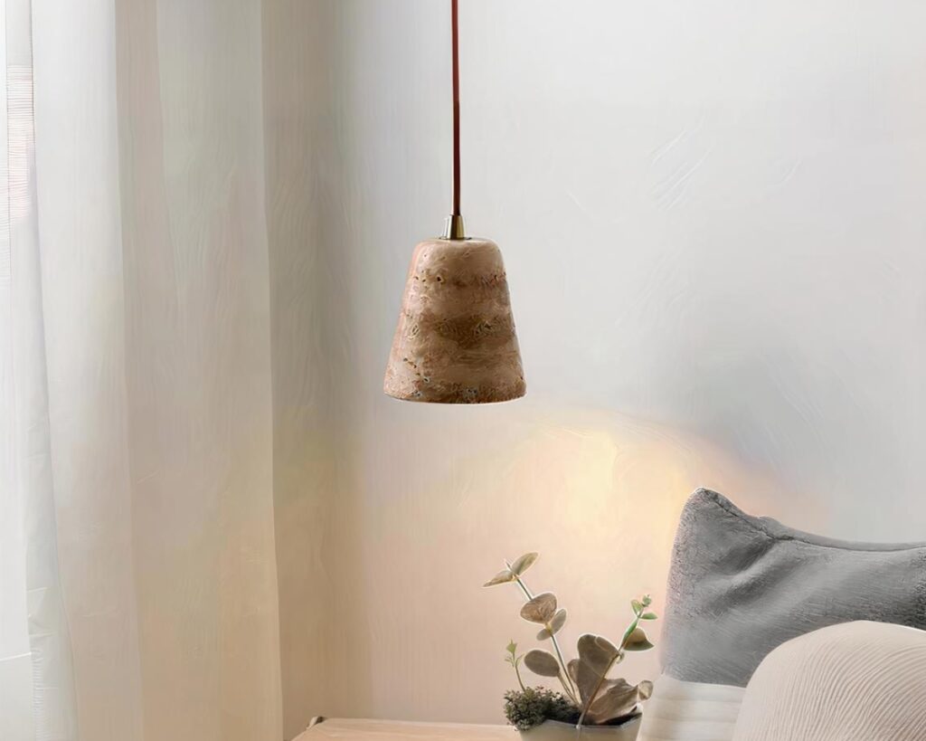 Suspension terre cuite avec effet marbré sur fond gris avec un coussin en bas à droite et une petite plante verte.