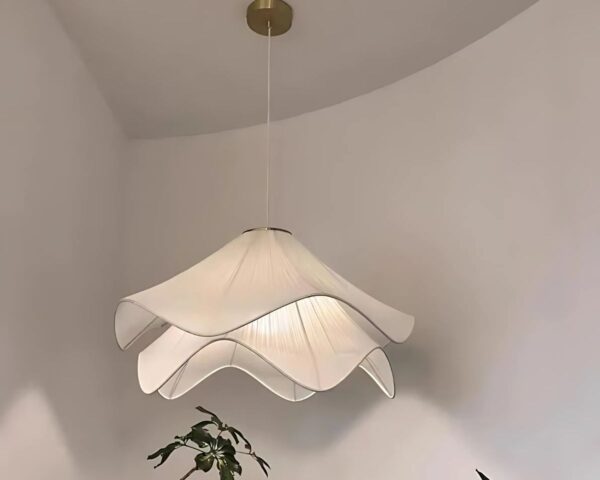 Suspension tissu élégante blanche, allumée et suspendue au-dessus d'une plante verte. Fond blanc.