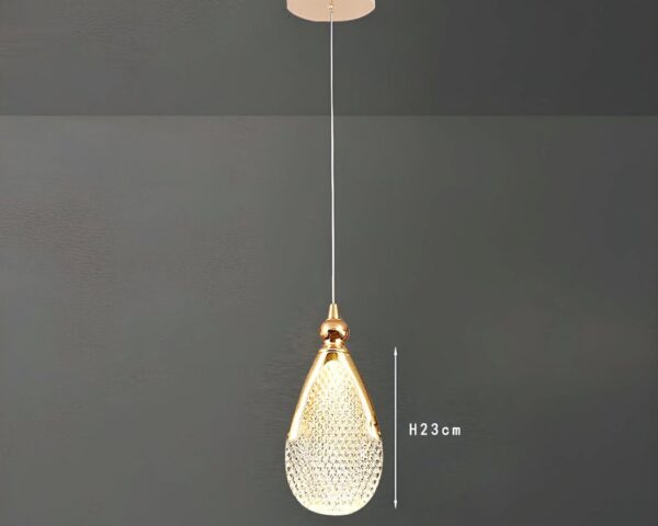 Une suspension goutte d’eau en acrylique doré avec un abat-jour en forme de goutte brillante, suspendue à un long fil sur fond gris.