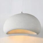 Une suspension Wabi-Sabi japonaise en résine blanche, en forme de galet arrondi, diffuse une lumière douce et chaude sur un fond clair.