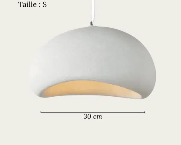 Une suspension Wabi-Sabi japonaise en résine blanche, en forme de galet arrondi, diffuse une lumière douce et chaude sur un fond clair.