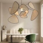 Une suspension en rotin tressé design bohème naturelle au-dessus d’une table, avec plusieurs abat-jour ajourés en rotin dans une salle à manger lumineuse.