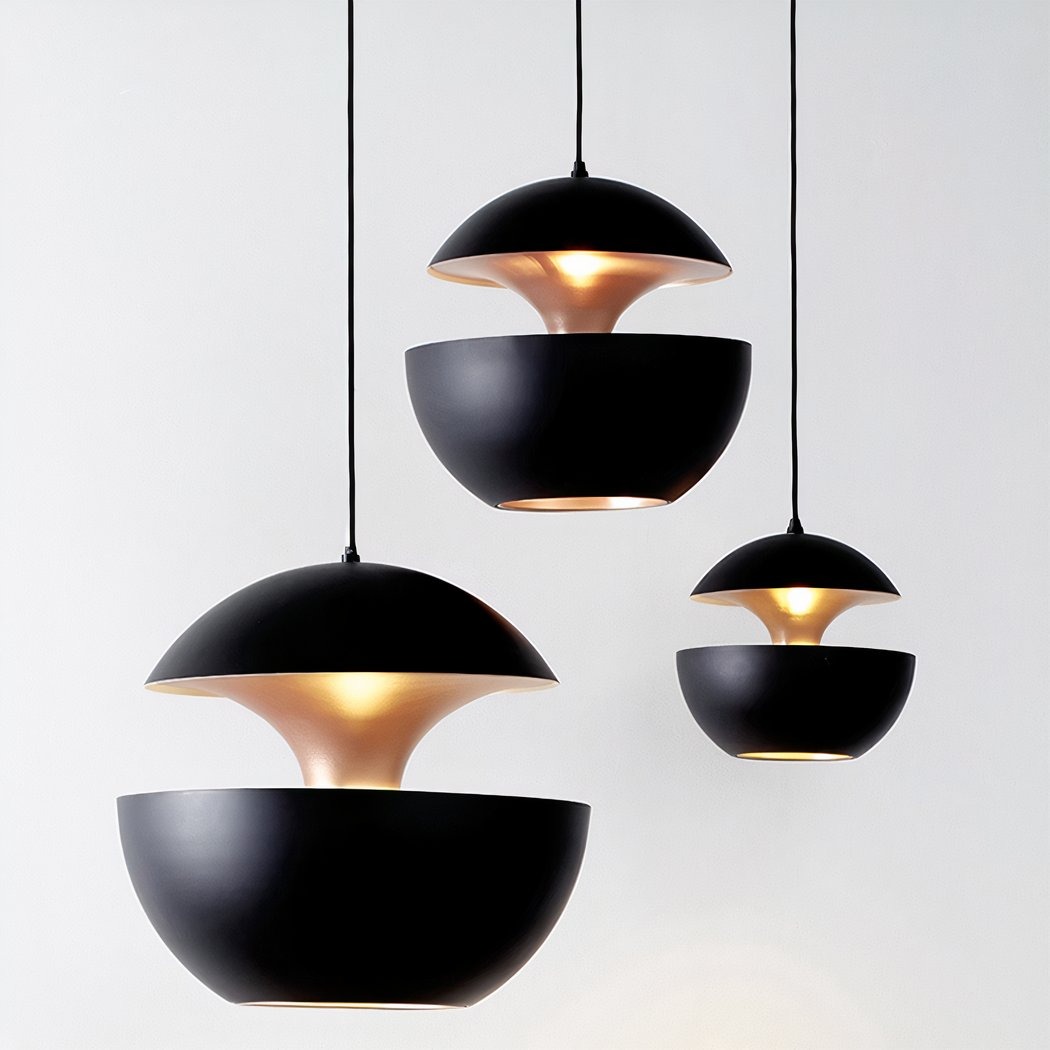 Trois suspension sphérique design à double coque blanc et doré, avec abat-jour noirs suspendus sur fond clair, diffusant une lumière chaude.