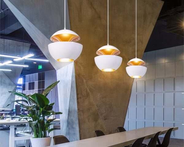 Trois suspension sphérique design à double coque blanc et doré, avec abat-jour noirs suspendus sur fond clair, diffusant une lumière chaude.