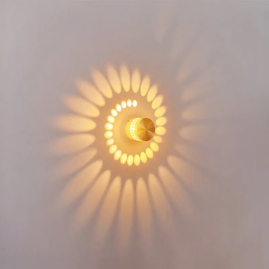Une applique murale LED à effet halo lumineux circulaire diffuse une lumière jaune douce sur un mur clair, avec un joli motif en forme de soleil autour.